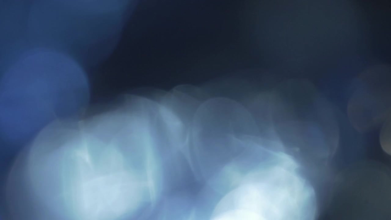 Ethereal Blue Light Leaks and Bokeh Shifting on a Black Background
