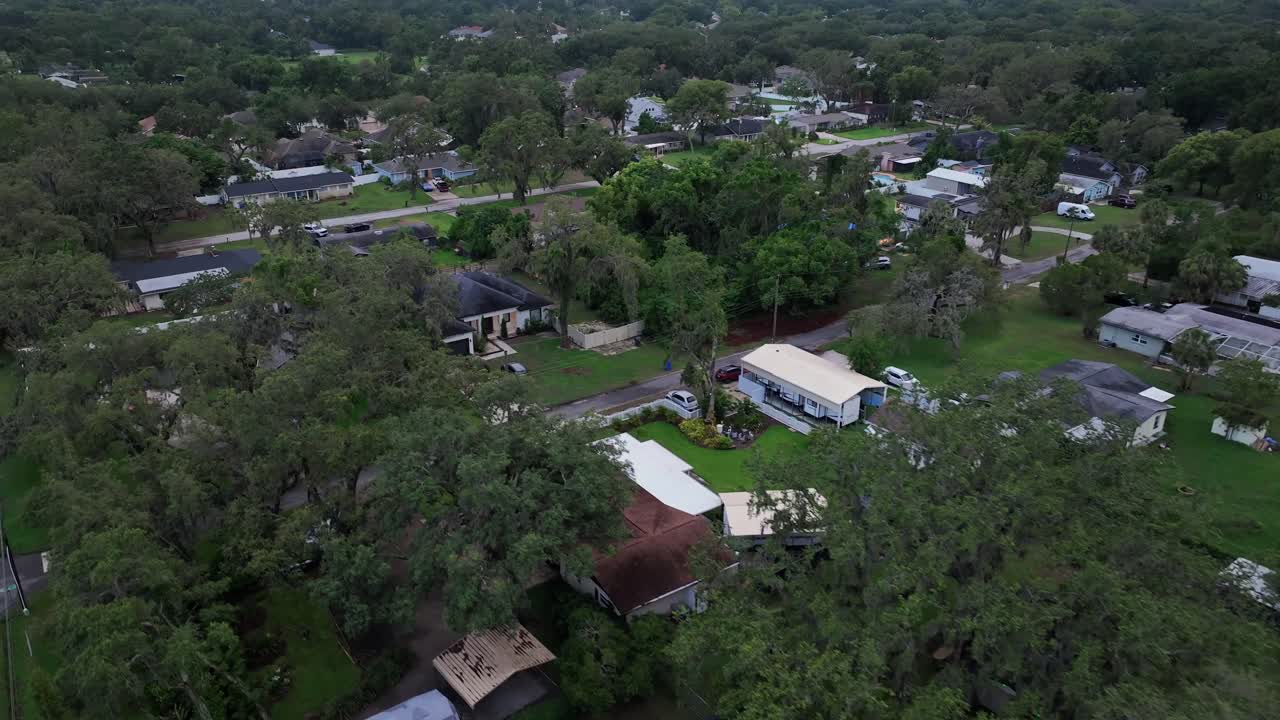 Aerial flyover quiet American neighborhood with houses at cloudy day. Suburbia of town in Florida. Green Grass in garden and yards