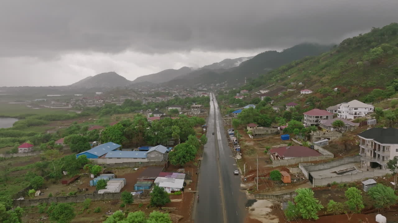 Aerial footage flying over a road on the coast of Sierra Leone right after the rain and everything is glistening