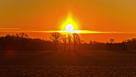 cinematic shot over a farmland in foreground and dense forest in the background during sunrise in timelapse