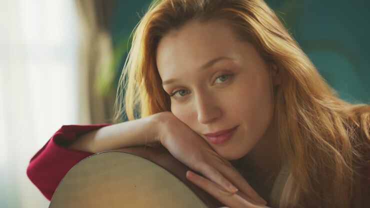 девушка смотрит в камеру с гитарой