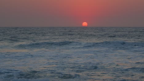 Slow-motion-Dramatic-pink-sunrise-reflected-over-breaking-waves-at-the-beach,-Durban,-Kwazulu-Natal