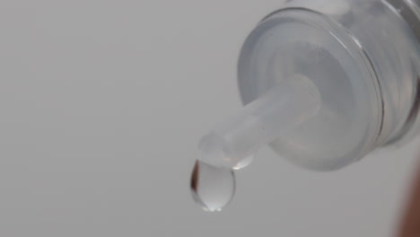 Close-up-Macro-Shot-Of-Water-Slowly-Dripping-Out-Of-A-Bottle-With-A-White-Background