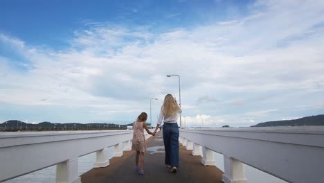 mother and daughter walking on a pier