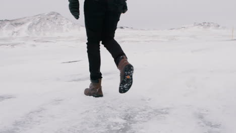 person walking on icy ground in snowy icelandic landscape