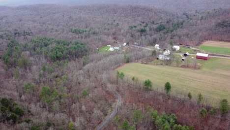 Traveling-over-the-tops-of-the-trees-of-the-forest-and-farmland-in-the-winter-season-aerial-view