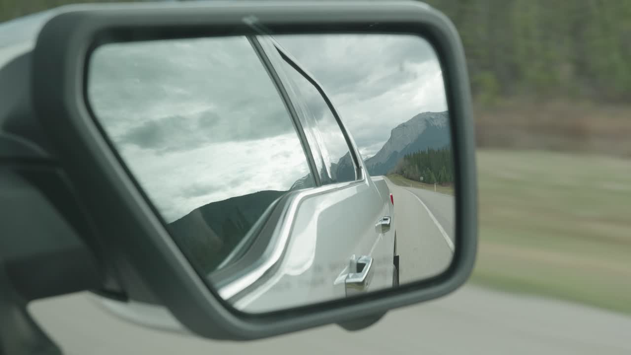 Close up shot to a car mirror looking back