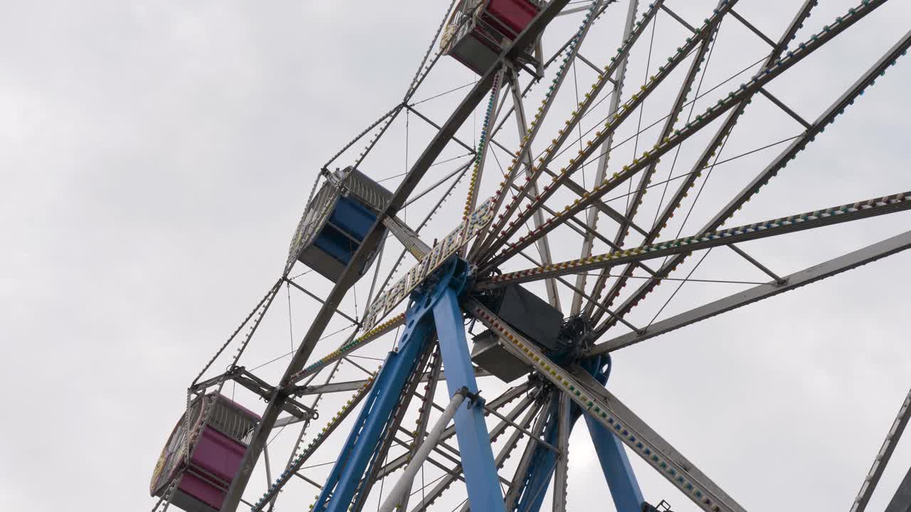 Slow motion close up of spinning ferris wheel carnival ride attraction showing steel beams and lighting mechanics at amusement park The Entrance foreshore Central Coast Australia entertainment circus