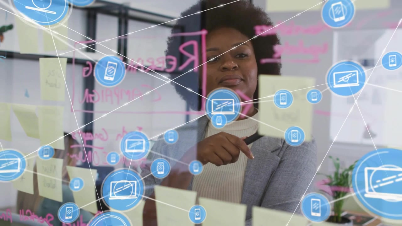 Woman leading business planning writing on glass and initiating blue icons linking and overlaying