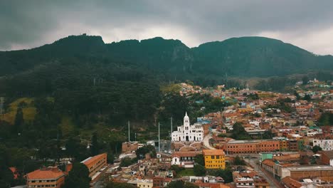 Drohnenansicht-Einer-Der-Straßen-Im-Zentrum-Von-Bogotá,-Kolumbien,-Mit-Kolonialhäusern-Und-Dem-Berg-Monserrate-Im-Hintergrund