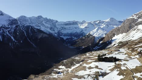 Aerial-View-of-the-"Cirque-de-Gavarnie"-in-the-Pyrenees-mountains,-France,-A-formidable-and-beautiful-wall-of-ice-and-rock-looms-in-the-background,-the-village-of-Gavarnie-is-in-the-valley-below