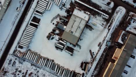 top-down aerial view of trucks, trailers, and tanks parked in an outdoor warehouse during winter