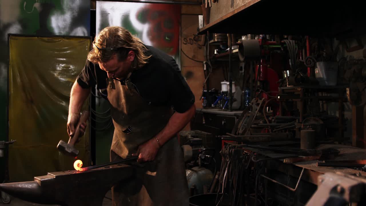 herrero trabajando en una barra de hierro
