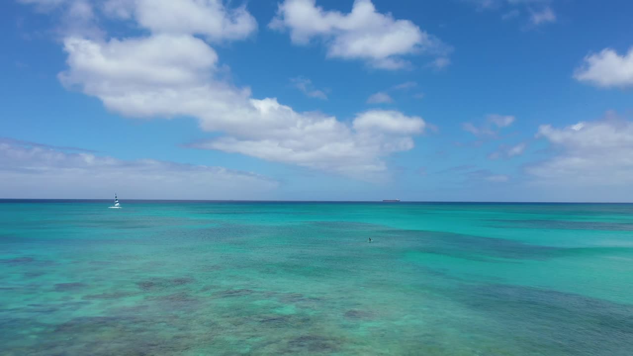 Scenic ocean view with a small boat sailing on clear blue waters under a partly cloudy sky near Waikiki Beach, Oahu, Hawaii. Ideal for tranquil beach and water activities