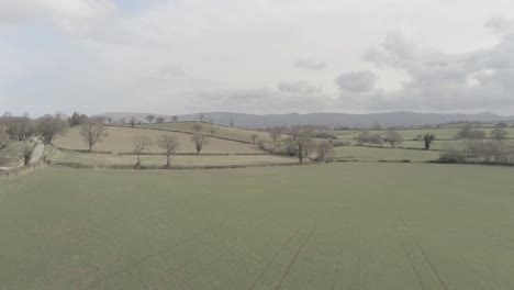vista aérea a través de idílicas tierras de cultivo de pastos agrícolas galeses empujar hacia abajo