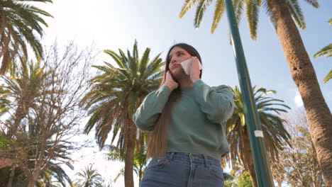 worried young woman using mobile phone in the street and then raising her hand to stop a taxi or a bus