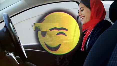 animation of happy emoji over woman in hijab using smartphone