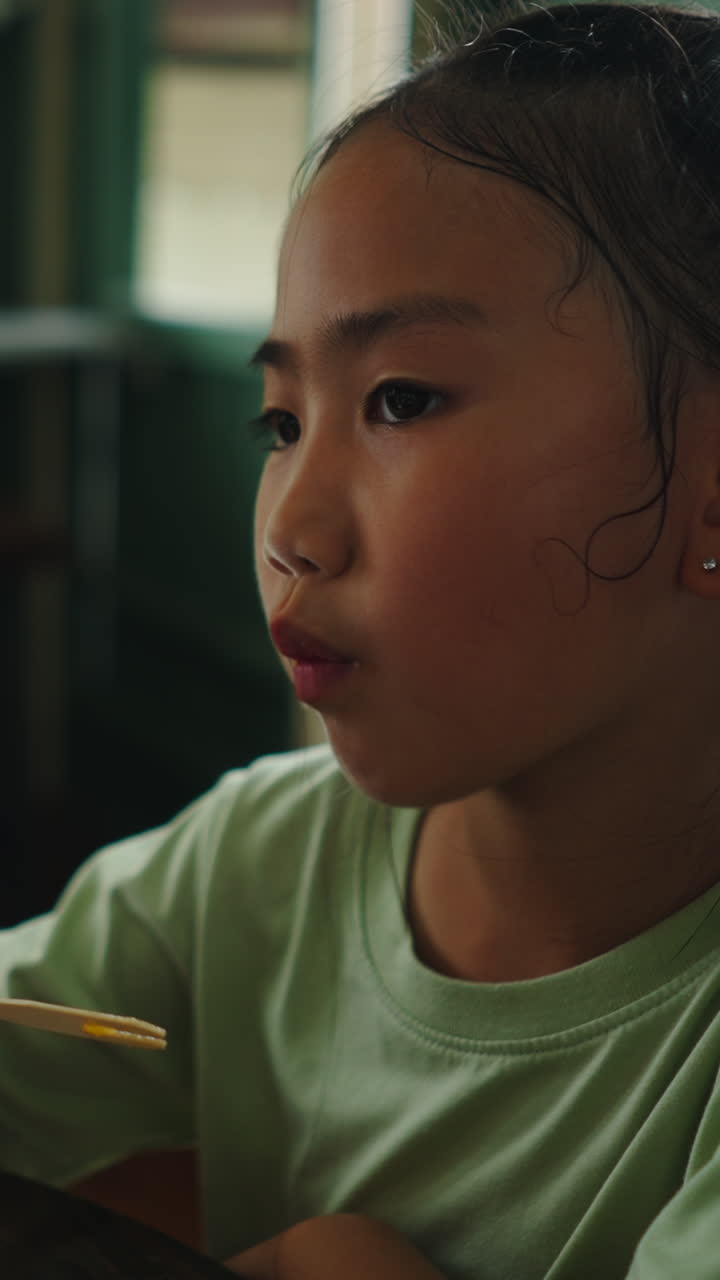 Primo piano di una giovane bambina asiatica che mangia uno spuntino