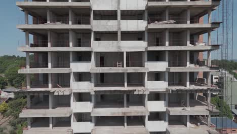 Drone-footage-traces-the-progress-of-a-building-under-construction,-view-from-the-top-floors-to-the-bustling-activity-at-ground-level,-capturing-every-detail-of-the-evolving-structure