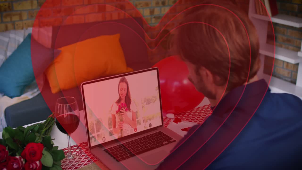Cuori rossi concentrici che si formano su un uomo caucasico che saluta mentre fa una videochiamata sul laptop