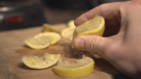 a person squeeze the lemon on a wooden board - close up shot