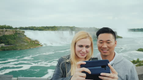 una joven pareja multiétnica admira una hermosa vista de las cataratas del niágara en américa y cana