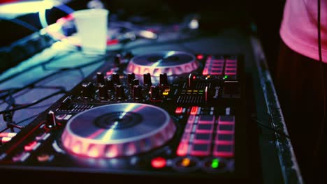 Close-Up,-Panning-Sot-of-DJ-mini-mixer-with-male-hands-of-DJ-playing-music-tracks-at-nightclub