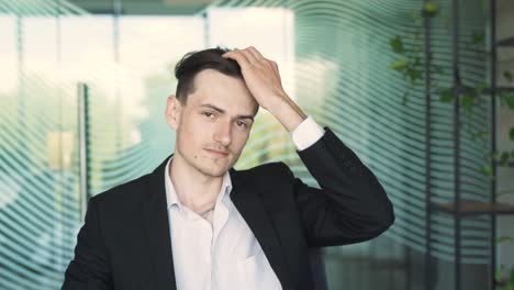 retrato en primer plano de un hombre guapo, joven y elegante en ropa de negocios, sentado en un escritorio con una computadora portátil en una oficina moderna