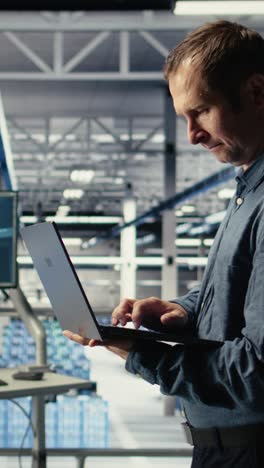vertical video technician monitors server room activity using laptop while walking in facility