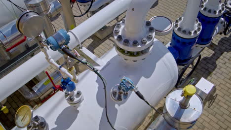 close-up of industrial gas pipeline with sensors, gauges, and control valves in a paved facility