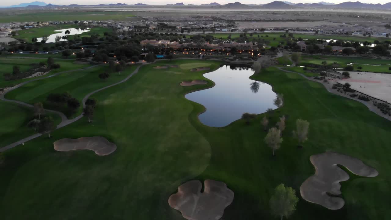 Drone footage from a golf course near a residential neighborhood in Arizona. High aerial shot of the greens, fairway and water hazard