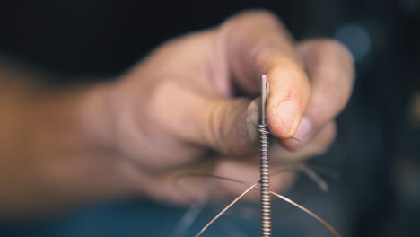 goldsmith takes off spiral from stick in workshop close view