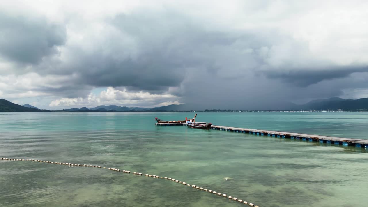 Thailand beach. Fishing boats are tied to a wooden dock at a serene Thai beach, with calm waters and a bluish-grey sky. Coastal life, natural beauty, tropical atmosphere. Travel, nature and seascapes.