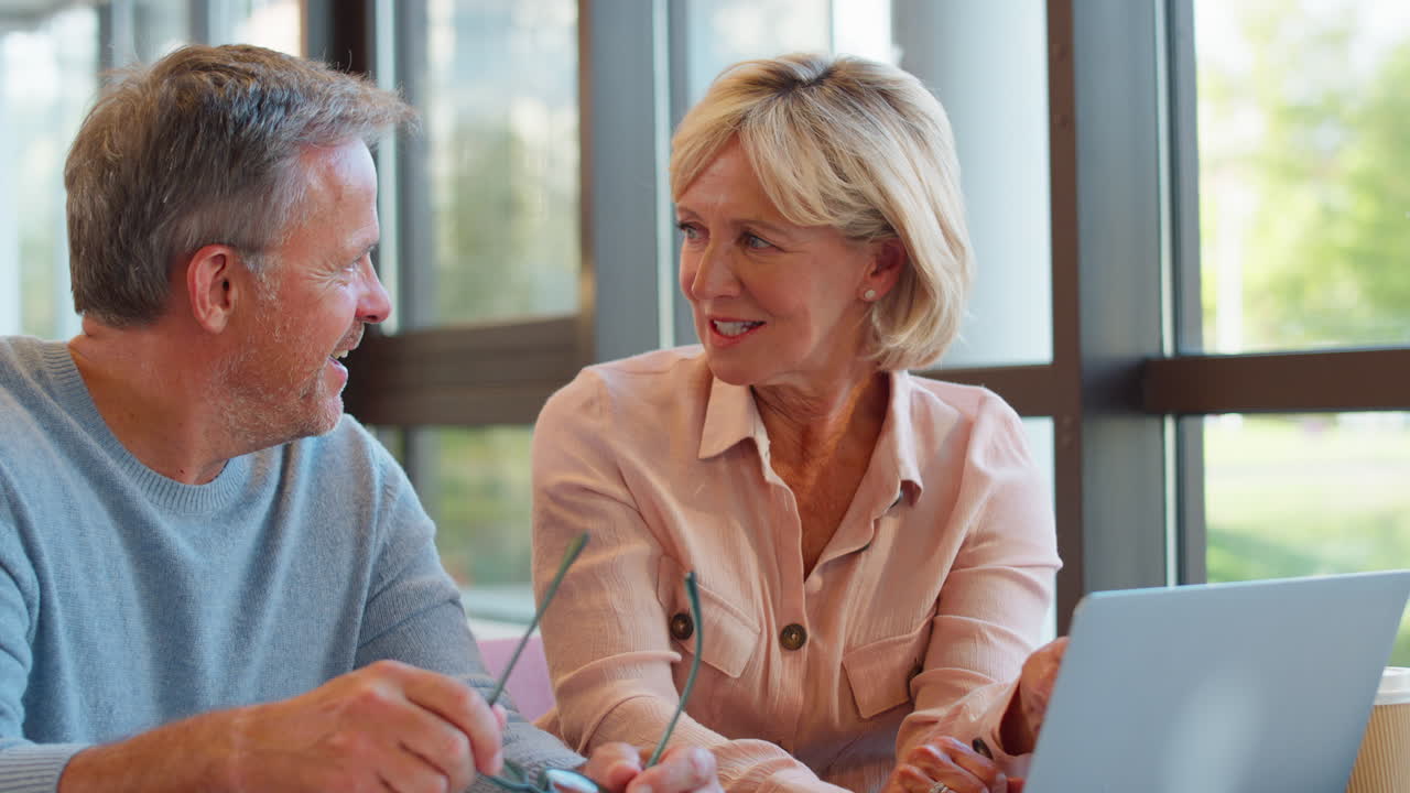 hombre de negocios maduro con una colega que se reúne en un escritorio con una computadora portátil