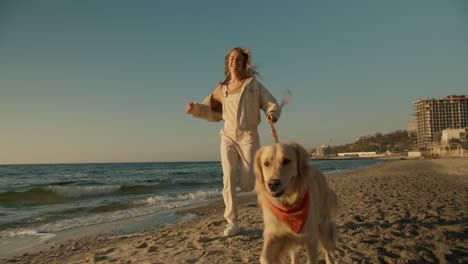close-up shot of a happy morning run with your dog. blonde girl runs with her dog on a sunny beach in the morning