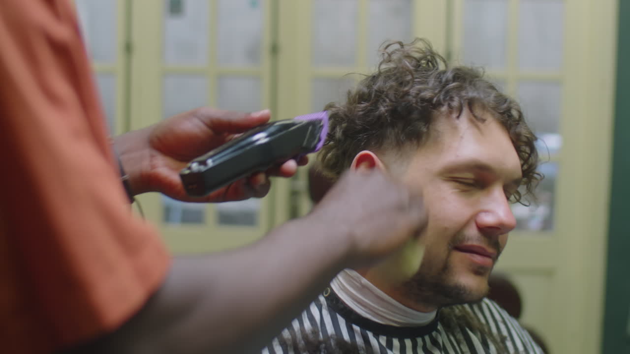 Barber Shaving Temples of Male Client with Hair Trimmer
