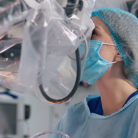 female doctor looks into the microscope during surgery. professional surgeons performing operation using modern medical equipment.