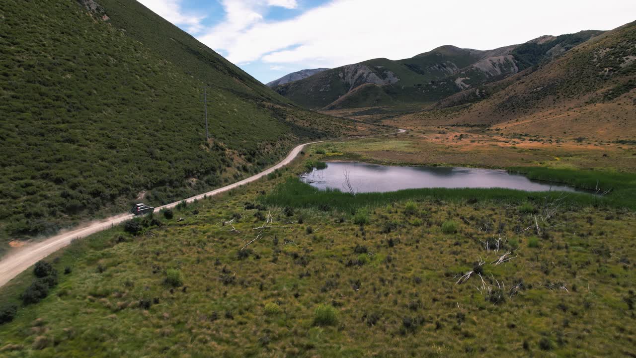 Drone following a vehicle driving at Lake Coleride high country, cloudy day in NZ
