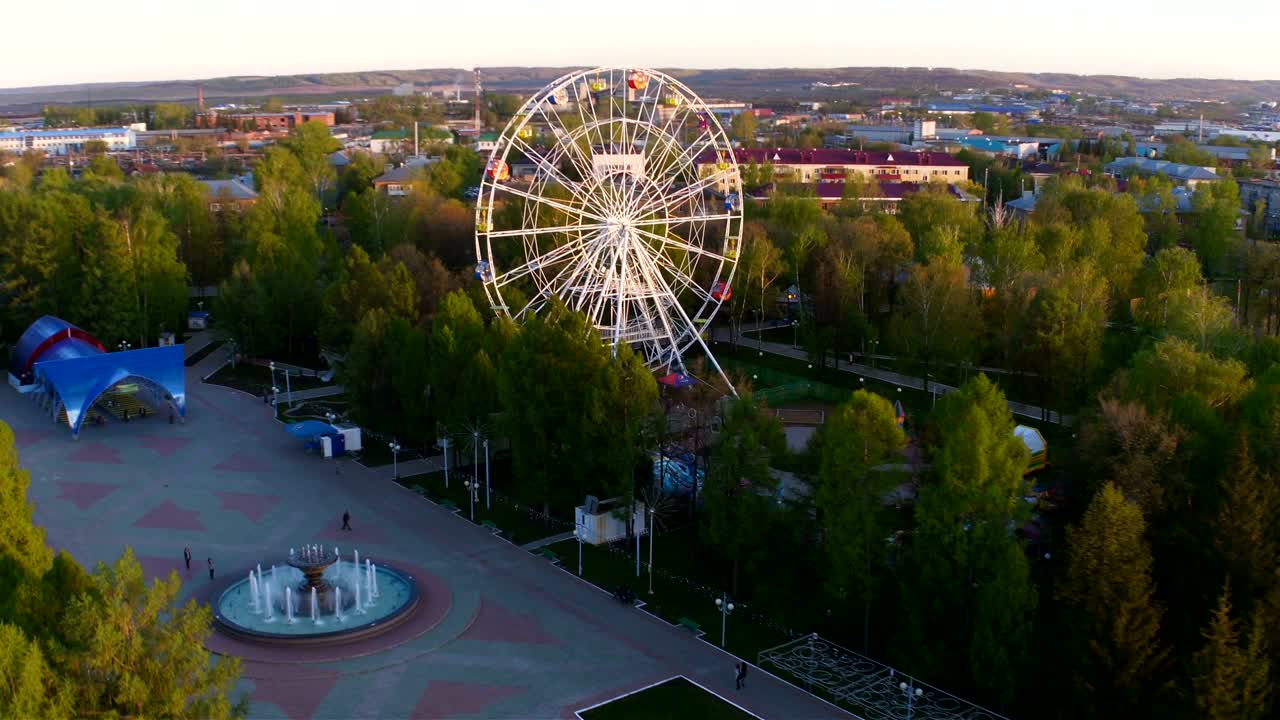 парк с рельсами и большим белым колесом обозрения с воздуха