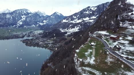 Majestic-hillside-road-during-heavy-snowfall-in-winter-season,-aerial-fly-back-view