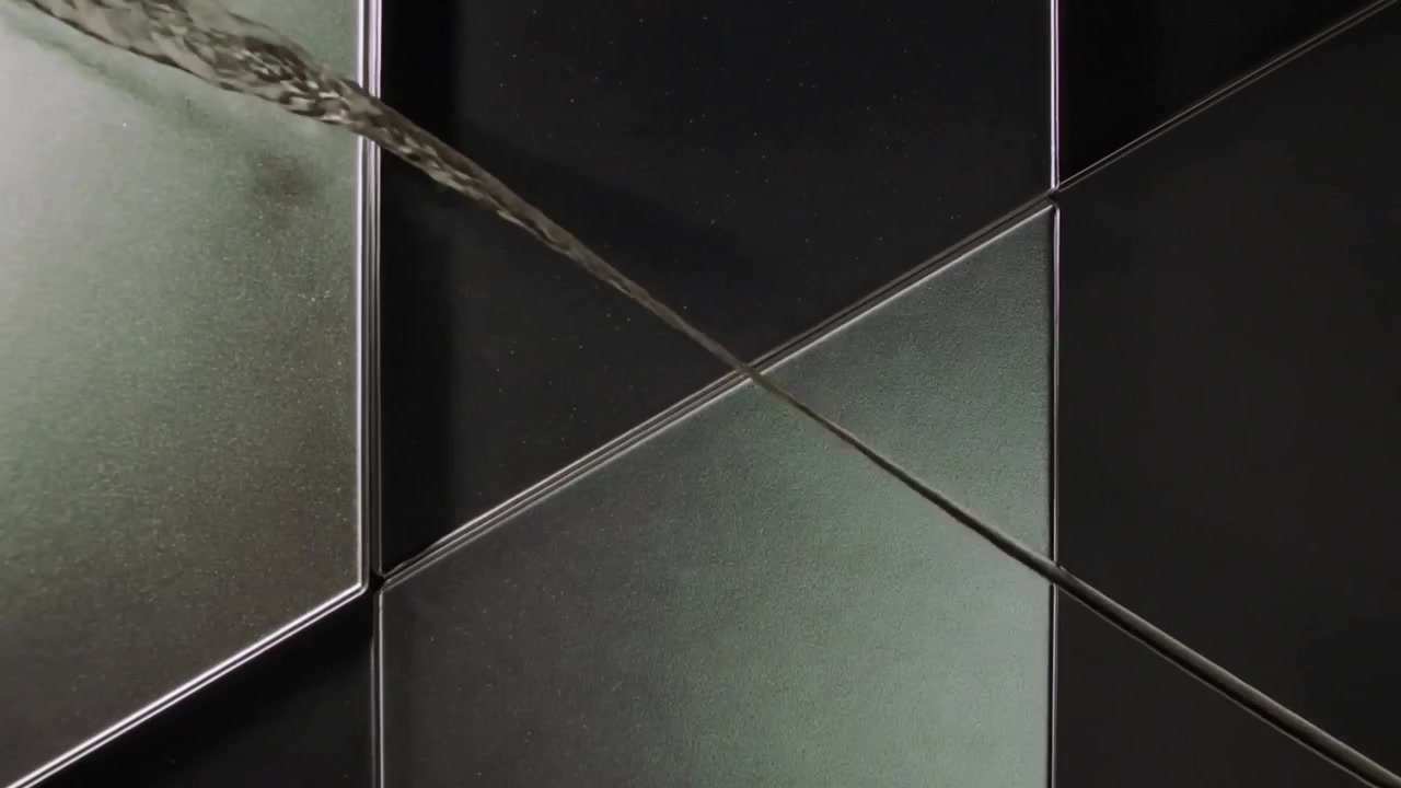 Formando un cordón diagonal delgado, una segunda línea formando una cuchilla plana que alisa la costura sobre paneles cuadrados brillantes.