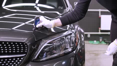 worker measures a thickness of primer on a car's body using a thickness gauge