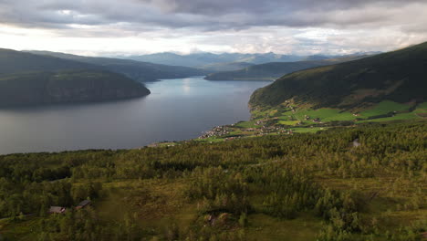 Luftaufnahme-Von-See-Und-Bergen-Mit-Blick-Auf-Ein-Dorf-Im-Tal-In-Norwegen-Mit-Ausgedehnten-Grünen-Flächen-Rundherum