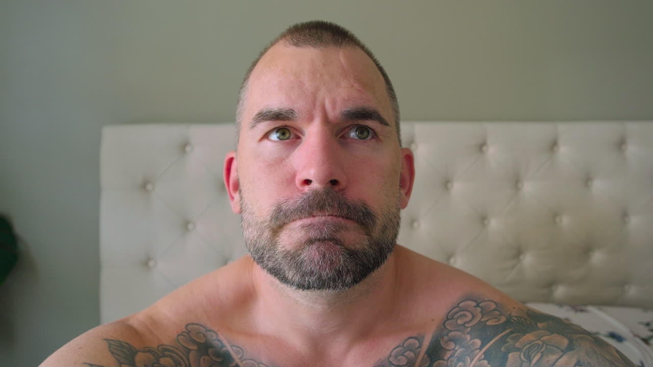 중년 백인 남자가 침실에서 깨어나고 있습니다.