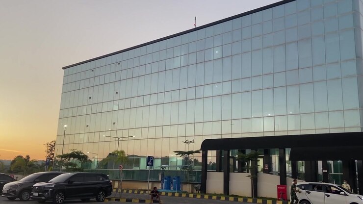 Esterno di moderno edificio in vetro con auto nel parcheggio al tramonto