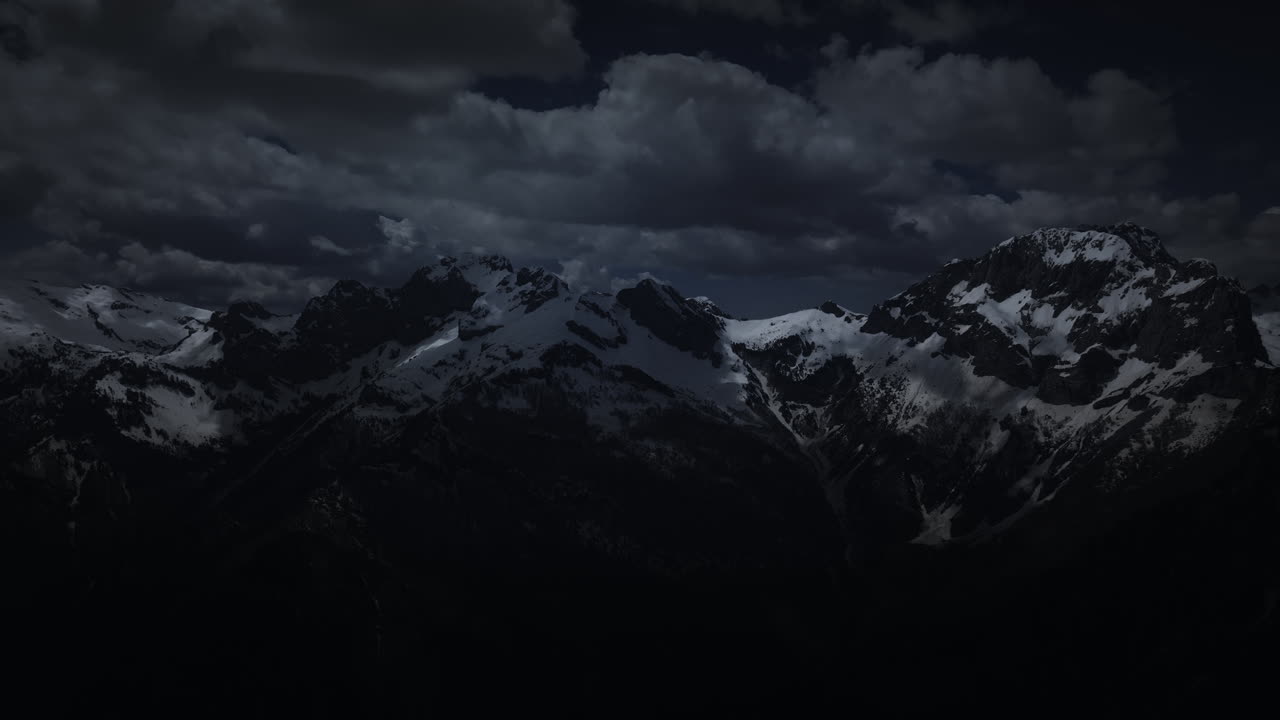 Snowy Mountains at Night Under Stormy Clouds