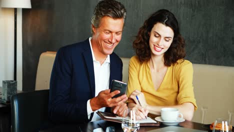 hombre de negocios sonriente y colega discutiendo por teléfono móvil