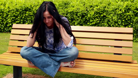 sad brunette thinking on bench in the park