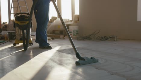 trabajador de la construcción limpiando un piso de hormigón en un nuevo sitio de construcción