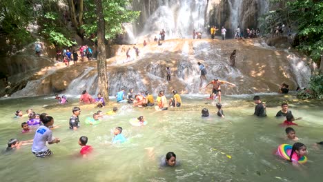 people swimming and relaxing at a waterfall